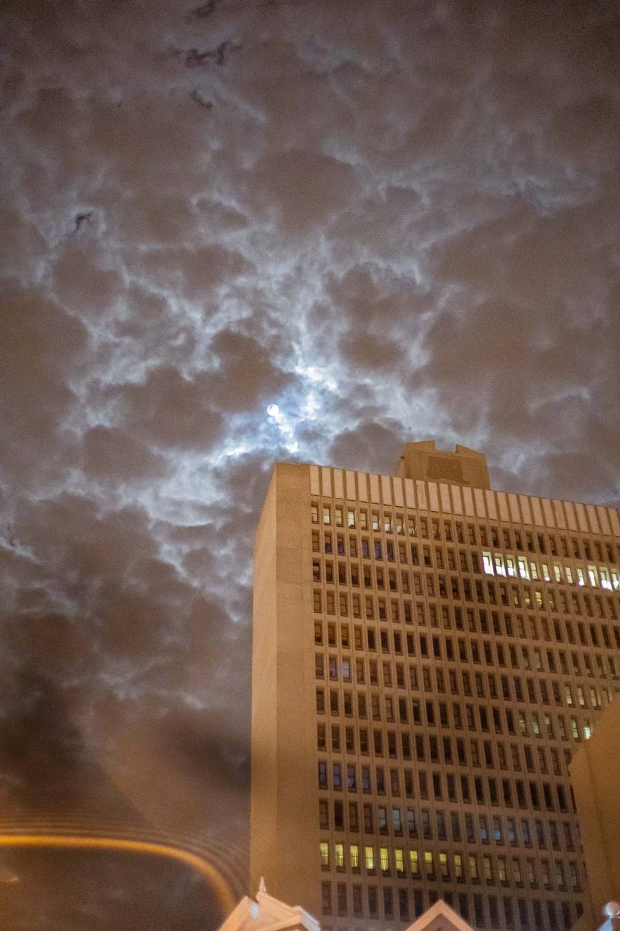 A tall building with many windows under a cloudy night sky