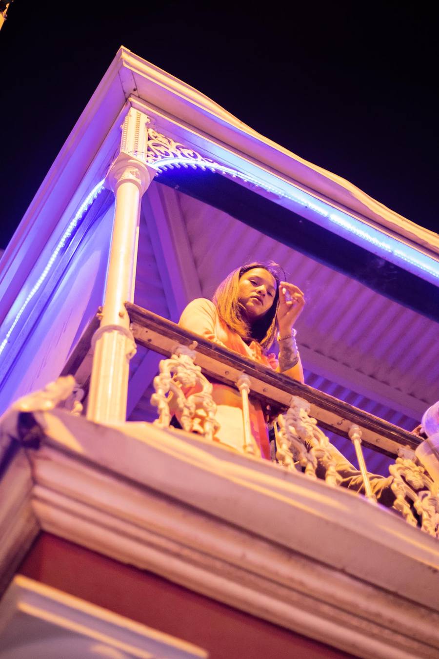 Woman on balcony with purple lights in background