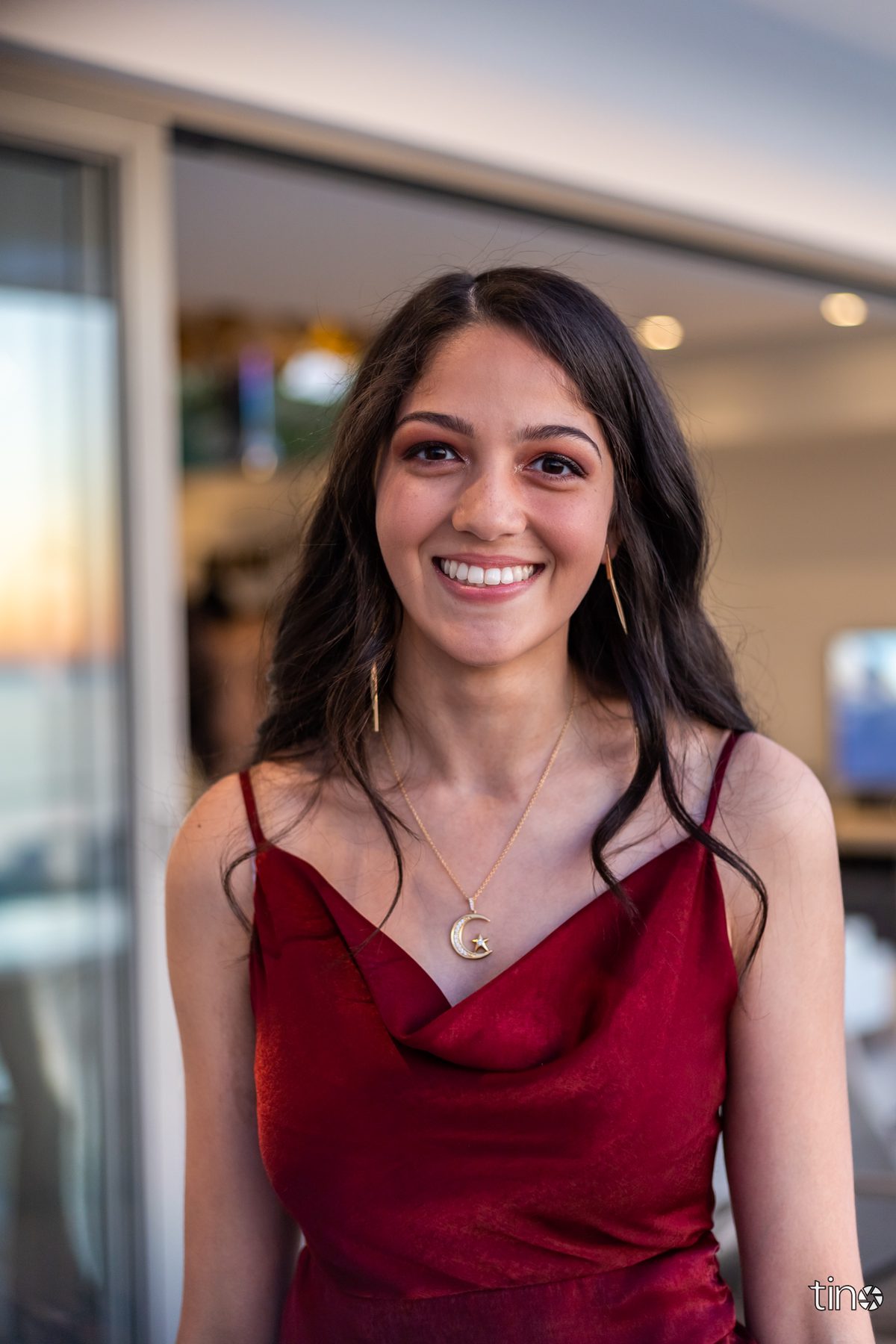 Woman in red dress smiling at camera with necklace and earrings