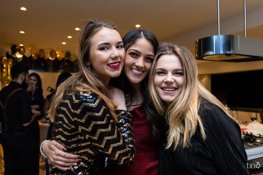 Three women smiling and posing for a photograph at a party