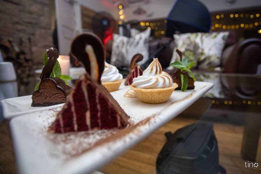 A white platter holds a variety of desserts including a chocolate cake and a meringue tart