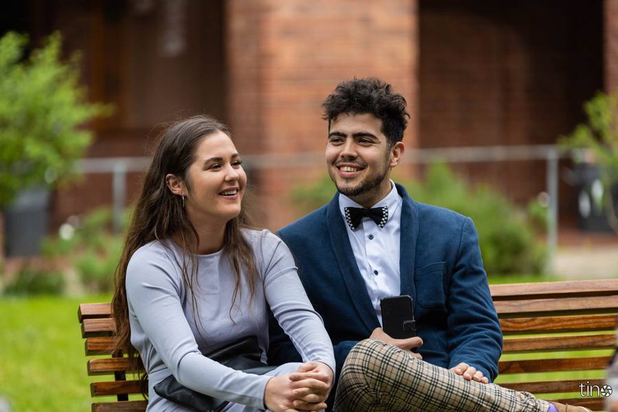 A couple sitting on a bench, smiling at the camera